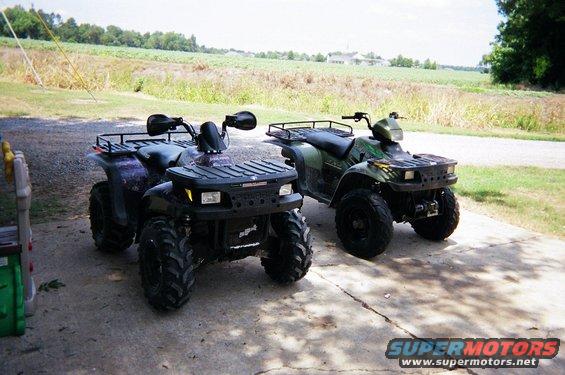 Two ATVs parked on a concrete surface with a field in the background