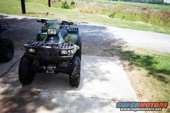Green ATV parked on concrete with another ATV to the left