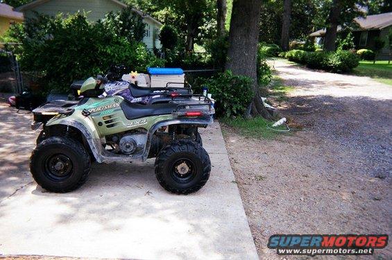 Green Polaris Sportsman 4x4 ATV parked on a concrete driveway