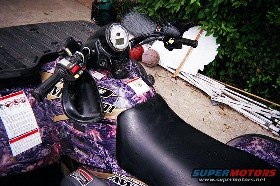 ATV handlebars, seat, and camouflage body. Two basketballs are behind the handlebars