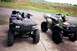 1995 Ford Bronco - Two all-terrain vehicles are parked side-by-side on a concrete surface, with a rural landscape visible behind them.