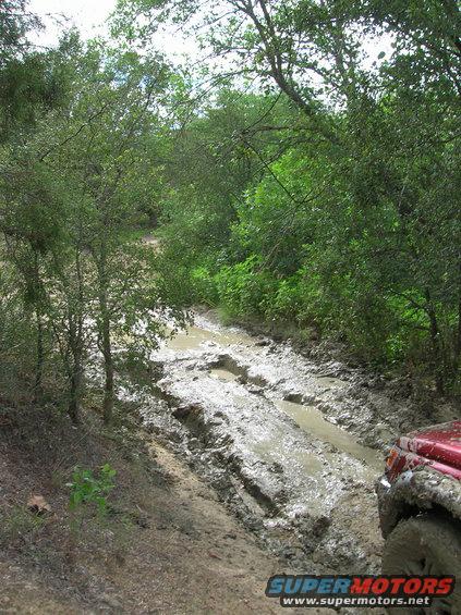 Red SUV on a muddy trail, right front fender and tire visible