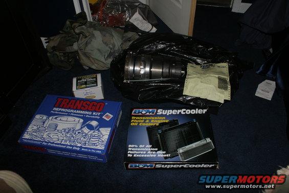 Boxes of Transgo reprogramming kit and B&M SuperCooler transmission oil cooler, plus a transmission part in a black bag