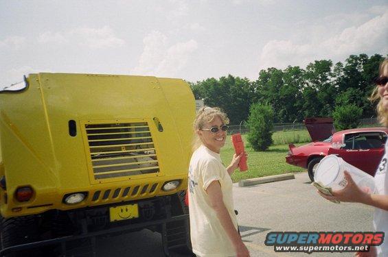 Yellow vehicle front with smiley face license plate, red car in background
