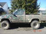 Camouflaged Toyota pickup truck with large off-road tires parked outside