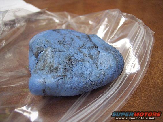 Blue detailing clay with dirt embedded in it, inside a plastic bag