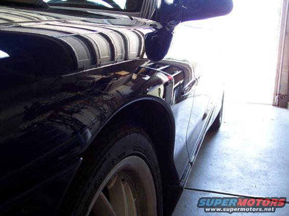 Dark car fender and side mirror, close-up side view