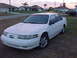 1994 Ford Taurus - A white 1994 Ford Taurus sedan is parked on a grassy area in front of a suburban house.