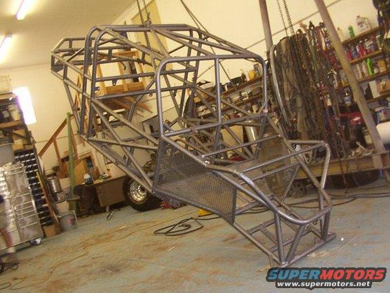 Custom tube chassis suspended in a workshop, showing a roll cage structure and a visible tire