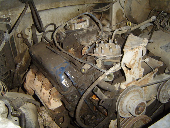 Dirty 1972 Ford F-100 engine bay with V8 engine, carburetor, and distributor visible