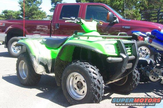 Green ATV parked in front of a red Ford F-350 truck. F-350 badge visible