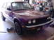 1984 BMW 3 Series - A purple 1984 BMW 3 Series coupe is elevated on jack stands inside a garage.