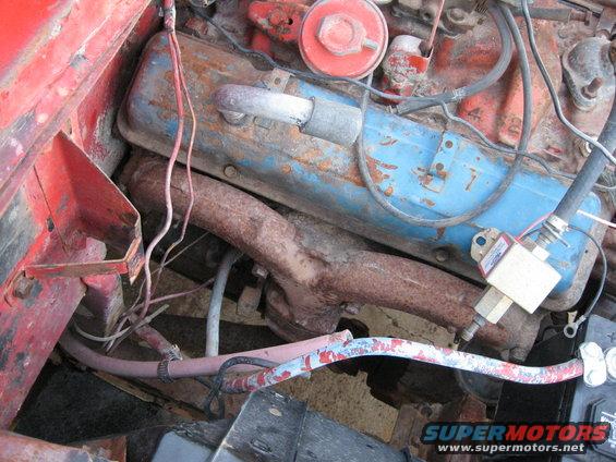 Close-up of a rusty engine bay with blue valve covers and red block