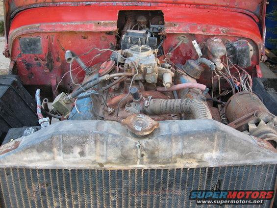 Red vehicle engine bay with visible carburetor and radiator