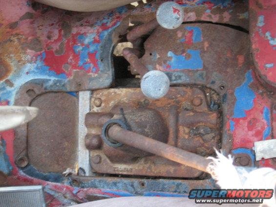 Rusted transmission housing with two shift levers and peeling red and blue paint