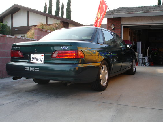 Dark green 1995 Ford Taurus sedan, rear 3/4 view, parked in driveway