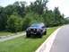 1996 Jeep Grand Cherokee - A modified 1996 Jeep Grand Cherokee sits on a grassy area next to a paved road with trees in the background.