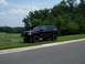 1996 Jeep Grand Cherokee - This lifted 1996 Jeep Grand Cherokee sits on a grassy verge next to a road, with a golf course visible in the background.