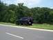 1996 Jeep Grand Cherokee - A black 1996 Jeep Grand Cherokee is parked on the side of the road with a spare tire mounted on the back.