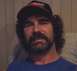 1990 Ford Bronco - A man with a beard and curly hair is wearing a baseball cap and a blue shirt.