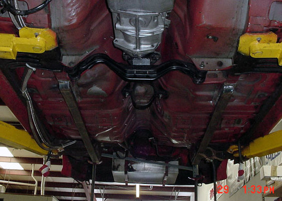 Underside of a car on a lift, showing the transmission and exhaust system