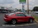 1996 Ford Mustang - A red 1996 Ford Mustang coupe is parked in a lot with other vehicles and businesses in the background.