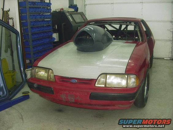Red 1990 Ford Mustang front view with large hood scoop and roll cage