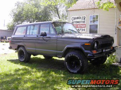 1977 Jeep Wagoneer parked in front of an automotive repair shop