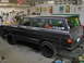 1977 Jeep Wagoneer - A 1977 Jeep Wagoneer is parked inside a garage, surrounded by tools and automotive memorabilia.