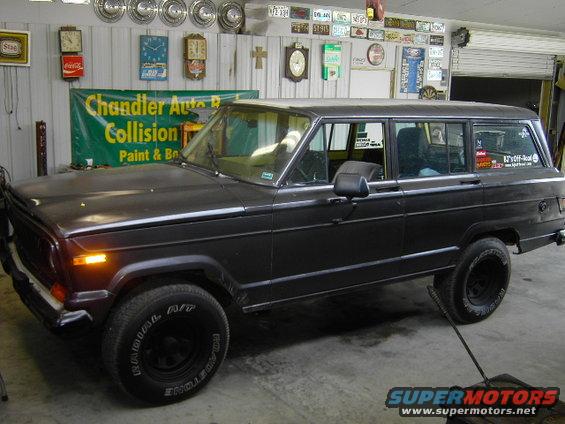 Dark-colored Jeep Grand Wagoneer parked in a garage with various items on the wall