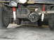 1977 Jeep Wagoneer - The rear suspension and drivetrain components of a vehicle are visible from underneath.