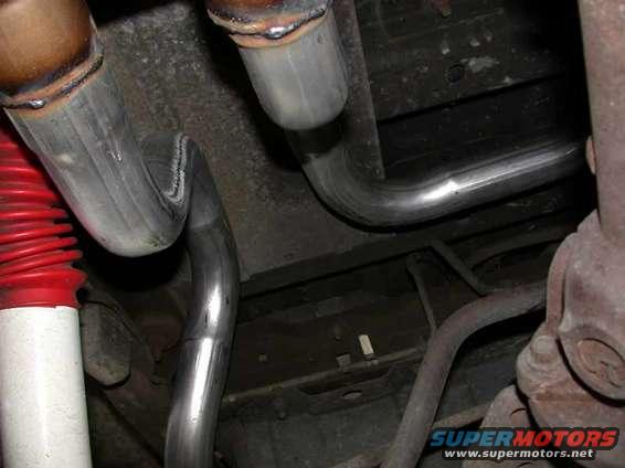 Underbody view of exhaust pipes and red-booted shock absorber