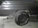 1977 Jeep Wagoneer - The rear passenger side of a Jeep Wagoneer shows significant rust damage near the wheel well and exhaust pipe.