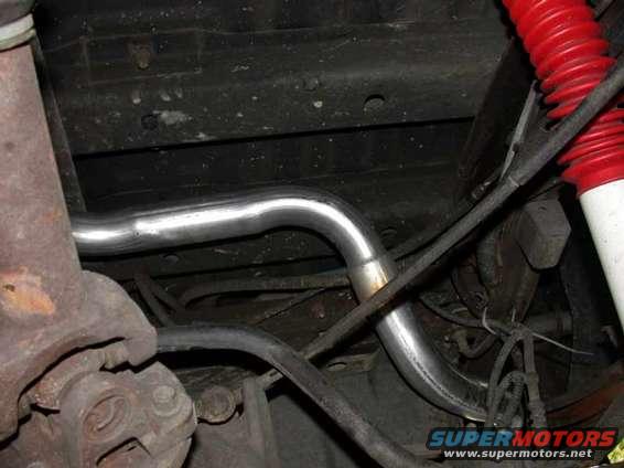 Underside view of a new exhaust pipe and red suspension components