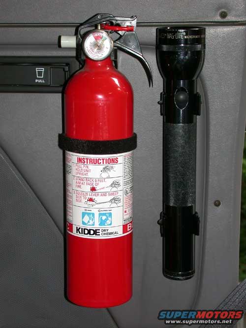 Kidde dry chemical fire extinguisher and Mag-Lite flashlight mounted on a gray car door panel