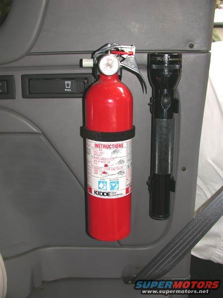 Red fire extinguisher and black flashlight mounted on gray interior panel