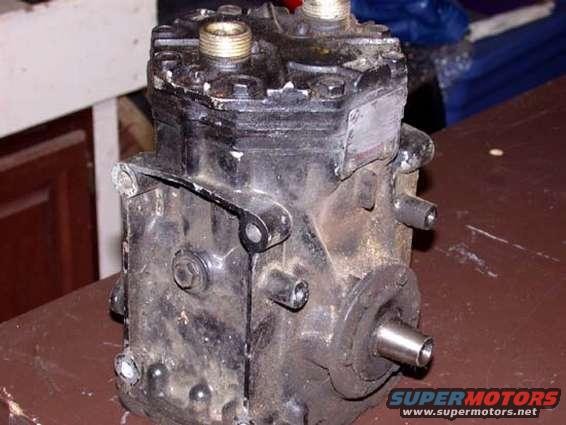 black air conditioning compressor with metal fittings and a shaft