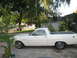 1966 Ford Ranchero - A white 1966 Ford Ranchero is parked in a driveway, showing its side profile with a handwritten number on the driver's side window.