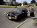 1985 Chevrolet Sprint - A man reaches for the door of a black 1985 Chevrolet Sprint with its hood open, parked on a residential street.