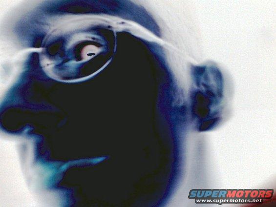 Close-up of a person's face in profile, wearing glasses. The image is inverted