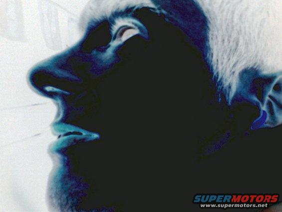 Inverted color photo of a person's face in profile, showing nose, mouth, and eye