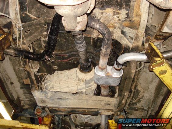 Underside of vehicle showing transmission, driveshaft, and exhaust system with muffler