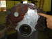 1993 Ford Taurus - Engine block part with a metal plate, showing rust and bolt holes.