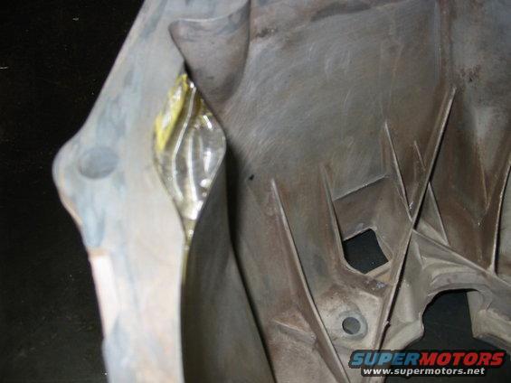 Close-up of a gray plastic automotive part with yellow tape visible in a crevice