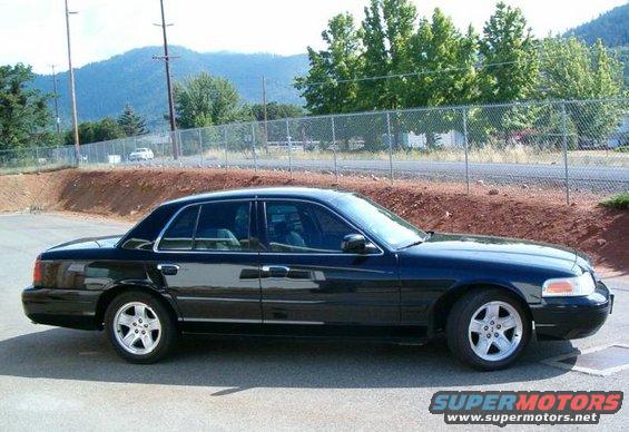 Black 2002 Ford Crown Victoria parked outside with trees and mountains in the background