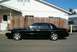 2002 Ford Crown Victoria - A black 2002 Ford Crown Victoria is parked next to a wooden fence, with a brown pickup truck visible in the background.