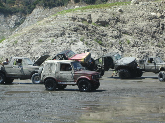 Red and tan 1987 Suzuki Samurai with soft top, off-road tires, and mud splatter