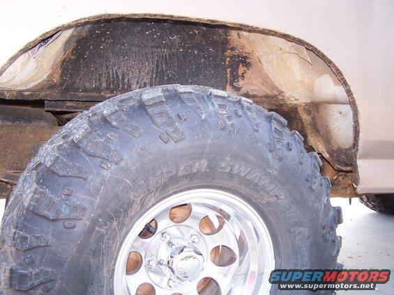 Close-up of a large off-road tire and the rusted wheel well of a vehicle