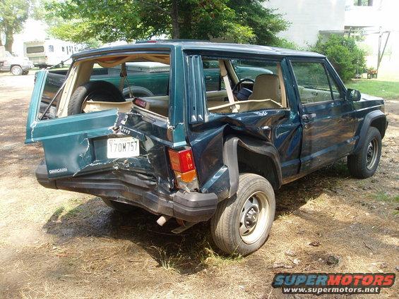 Rear view of damaged dark green Jeep Cherokee with license plate 170M757