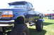 2006 Ford Supercrewzer - This lifted blue pickup truck features flame graphics and F250 badging, suggesting a model from the late 1990s.